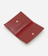 Billetera pequeña tipo sobre color bordó, confeccionada en poliuretano con textura capitoneada y aplique de corazón dorado.