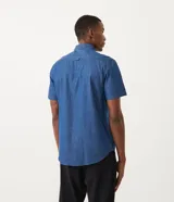 Camisa de manga corta confeccionada en tejido de algodón color azul denim, con cuello camisero, cierre frontal abotonado, bolsillo de parche en el pecho y corte comfort.