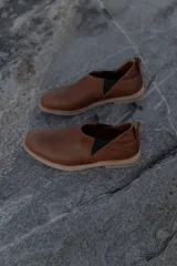 Mocasines marrones de cuero con elásticos laterales y tirador trasero.