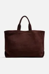 Bolso tipo shopper marrón de piel con acabado serraje. Tiene dos asas de mano y un bolsillo interior con cierre.
