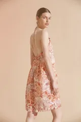 Vestido corto con estampado floral en tonos naranja y blanco, con cuello halter y volados en el ruedo.