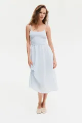 Vestido midi celeste con textura a rayas, cuerpo entallado fruncido, escote redondo y breteles spaghetti. Costura fruncida en la cintura y pollera con leve vuelo.