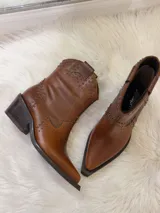 Botas cortas de cuero color marrón con punta fina, taco cuadrado y apliques de tachas metálicas.