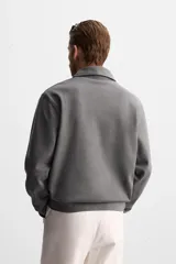 Polo manga larga gris con cuello solapa y cierre frontal de botonadura.