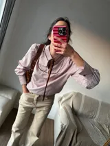 Camisa a rayas verticales rojas y blancas con cuello con solapa marrón y lazo al cuello.