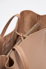 Bolso shopper negro de cuero con textura granulada, doble asa de hombro y logo blanco estampado en la parte inferior. Interior color caramelo con bolsillo con cierre. Cierre superior con lazo de cuero.