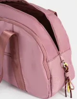 Bolso color beige de tela deportiva con manijas superiores y cierre superior. Tiene un bolsillo frontal con cierre y bolsillos laterales con cierre y tiradores de cordón y goma.