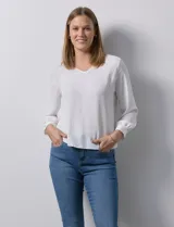 Blusa blanca de gasa marca Sioni, con escote en V y mangas largas con puño.