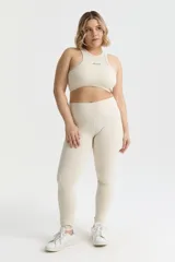 Top deportivo color crema con diseño halter, calce ajustado y almohadillas removibles.