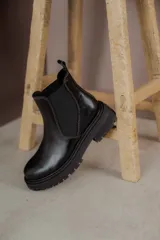 Bota Chelsea de cuero negro con elástico lateral y suela track.