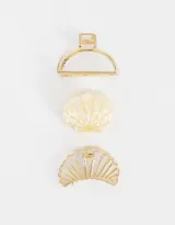 Set de tres broches para el pelo con forma de concha marina, dos de metal dorado y uno de resina color crema.