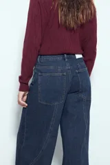 Jean ancho de tiro medio, color azul oscuro, con corte wide leg y paneles de costura visibles en las piernas.