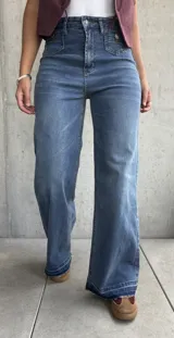 Jean de mujer color azul claro, de corte recto y tiro alto, con bolsillos delanteros decorativos con solapa y botón.