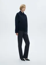 Pantalón de vestir negro con finas rayas verticales blancas, de tiro alto y corte recto.