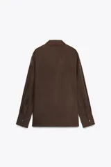Camisa marrón de seda 100% con cuello solapa, manga larga con puños abotonados, bajo asimétrico redondeado y cierre frontal con botones.