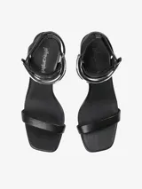 Sandalias de tacón negras con tira delgada sobre los dedos y pulsera tobillera con adorno tubular plateado.