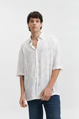 Camisa oversize blanca con estampado de hojas en color beige, cuello clásico y mangas cortas.