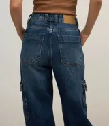 Pantalón wide leg de jeans con trabillas en la cintura, cierre por botón y cremallera, y bolsillos cargo.