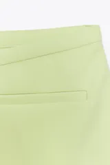 Falda pantalón corta color blanco, de tiro medio con bolsillos delanteros y cintura asimétrica. Cierre lateral con cremallera oculta.