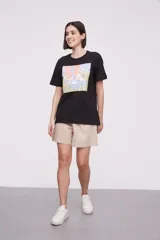 Remera negra con estampado de una mano sosteniendo una cartera rosa con flores.