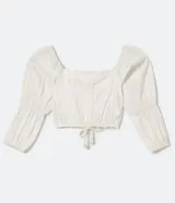 Blusa cropped blanca con escote cuadrado, mangas largas abullonadas con elástico en los puños, textura con hilo metalizado y amarre en la cintura.