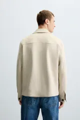 Sobrecamisa color beige de tejido efecto ante, corte regular fit, con cuello solapa, manga larga con puños abotonados, bolsillos de parche con solapa en el pecho y bolsillos de ojal en la cadera.