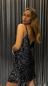 Vestido corto negro con lentejuelas plateadas, escote en V y breteles finos.
