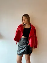Minifalda negra de ecocuero con diseño cruzado y detalle de argollas metálicas.