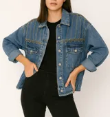 Campera de jean azul con detalles de cadenas doradas en los hombros y bolsillos frontales.