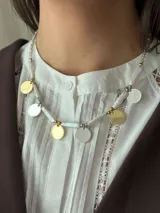 Collar corto con perlas de río naturales, cuentas metálicas de acero quirúrgico, medallitas bañadas en plata y oro y mostacillas. Se cierra con cadena de acero quirúrgico y ganchito para regular el largo.