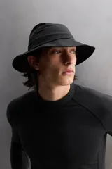 Sombrero tipo bucket color beige, confeccionado en tejido técnico con perforaciones en la copa para mejorar la transpirabilidad. Tiene ajuste elástico y ala ancha con pespuntes.