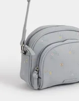 Bandolera de cuerina color celeste con bordado de flores y bolsillo frontal con cierre.