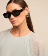 Blusa celeste de crepé con textura plisada, cuello redondo, mangas largas abullonadas y puños ajustados.