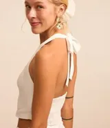 Blusa chaleco color blanco, con frente única, lazo en el cuello, lastex en la espalda y botones delanteros.