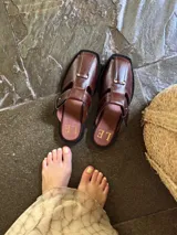 Sandalia de cuero negro con diseño abierto y correa con hebilla.