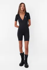 Mono corto negro de microfibra con calce slim, cuello polo, escote en V pronunciado, cierre frontal y mangas cortas.