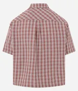 Camisa de manga corta con cuello inglés, corte oversized y estampado de cuadros en tonos rojo, blanco y negro.