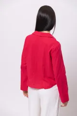 Camisa color beige de corte corto, con cuello clásico, abotonada al frente y mangas largas.