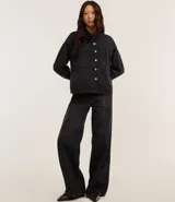 Camisa de jean negra con abotonado delantero, cuello solapa, mangas largas, recortes y bolsillos grandes en el pecho.