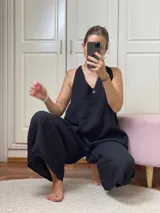 Mono negro de lino, con escote en V, tirantes anchos y corte holgado en las piernas.