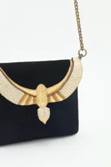Cartera de mano negra de cuero gamuzado con solapa bordada con diseño de alas en tonos dorados y plateados. Tiene cierre magnético, bolsillos internos y cadena metálica dorada vieja.