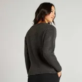Sweater gris oscuro de punto tricotado con cuello redondo y mangas largas. Tiene aberturas laterales con cadena dorada.