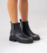 Botas Chelsea de cuero vacuno negro con elásticos laterales, cierre interno y suela de goma artesanal.