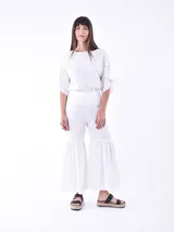 Pantalón blanco de corte cropped y ruedo acampanado con volantes.