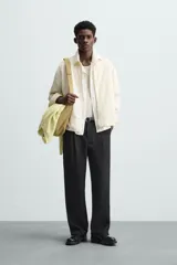 Sobrecamisa color crema de tejido técnico ligero, corte regular fit, cuello solapa, manga larga con puño abotonado, bajo ajustable con elástico en laterales y cierre frontal con cremallera.