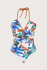 Traje de baño entero con estampado tropical de hojas en tonos azules, verdes y marrones sobre fondo blanco. Presenta escote en V profundo con ribete color marrón y frunces laterales para realzar la silueta. Se ata al cuello con tirantes finos color marrón.