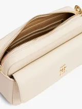Bandolera Tommy Hilfiger color crema con logo de la marca en dorado en el frente.