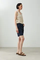 Bermuda azul marino de corte recto, con cinco bolsillos y cierre frontal con botón y cremallera.