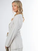 Conjunto color beige de lino, compuesto por un blazer cruzado con lazo para atar y un pantalón de corte recto con cintura elástica.