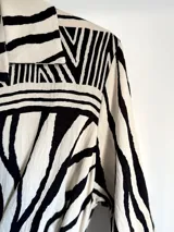 Vestido camisero con estampa acebrada en blanco y negro, de calce oversized y talle único. Incluye lazos para ajustar al cuerpo.
